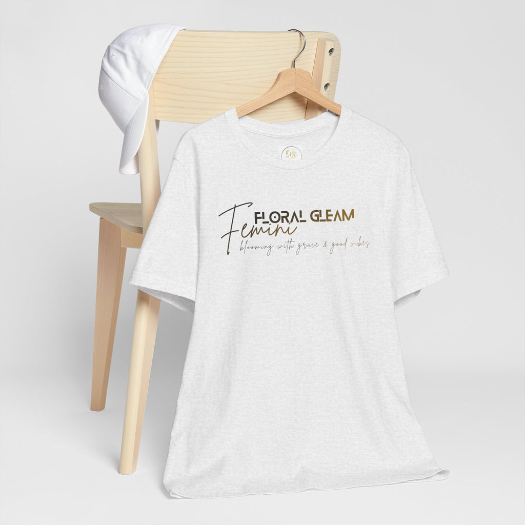 White t-shirt with 'Floral Gleam' text on a wooden chair against a white background